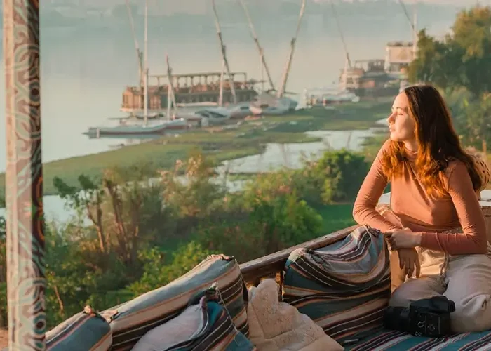 Girl sitting by the Nile River in Aswan, Egypt, enjoying the scenic view.