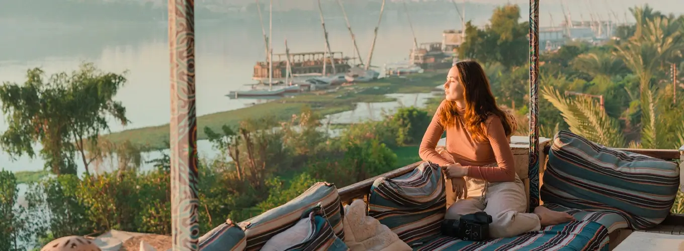 Girl sitting by the Nile River in Aswan, Egypt, enjoying the scenic view.