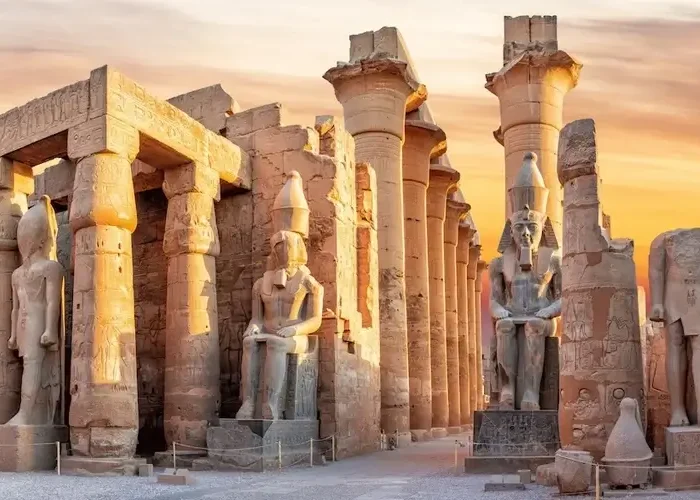 Luxor Temple illuminated at sunset with vibrant colors in the sky.