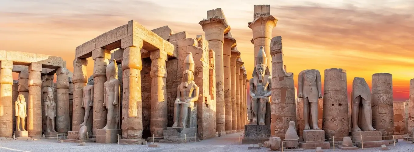 Luxor Temple illuminated at sunset with vibrant colors in the sky.