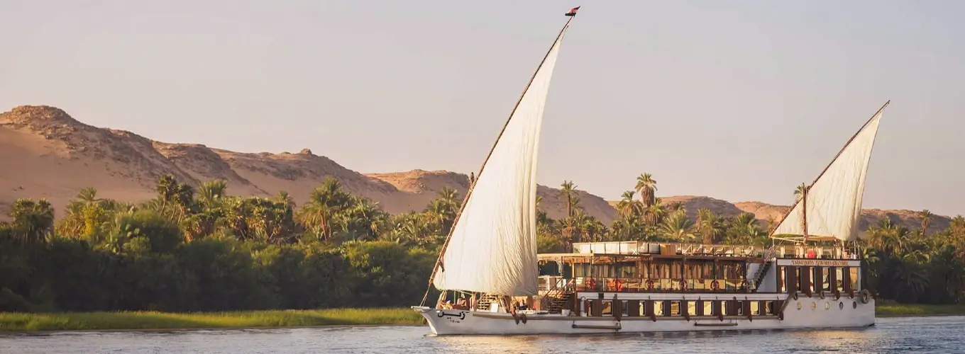 Dahabiyas sailing on the Nile River under a clear blue sky