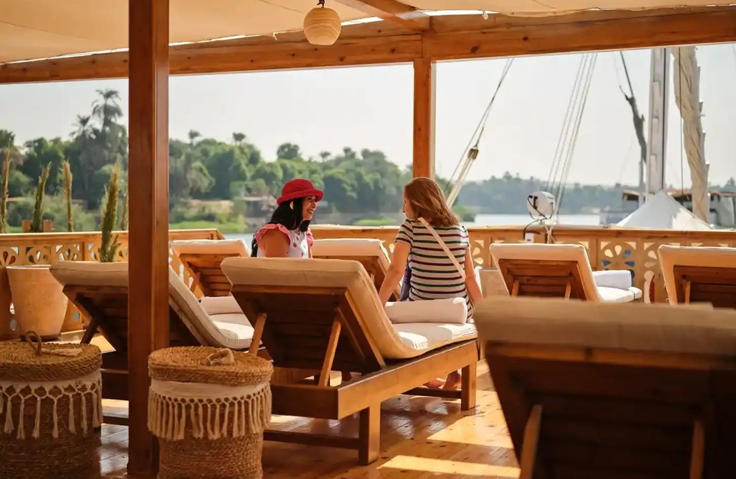 Learn What a Dahabiya Nile Cruise - Nile Cruise Offers 2 A wonderful picture of two girls sitting inside a Nile cruise on a dahabiya