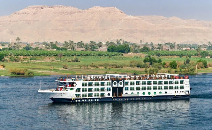 Cruise ship named Mayflower sailing on calm waters during sunset