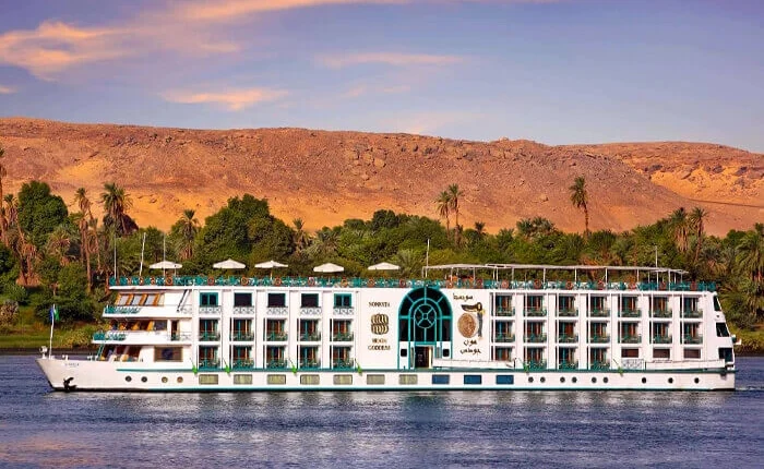 Luxury cruise ship Sonesta Moon Goddess on a scenic waterway at sunset.