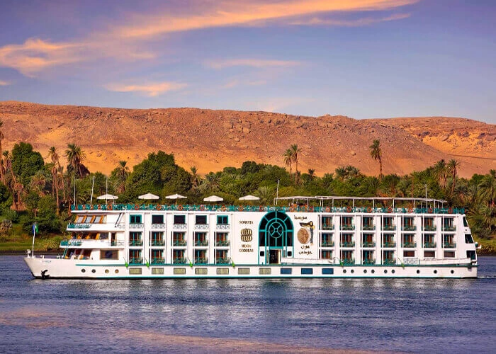 Luxury cruise ship Sonesta Moon Goddess on a scenic waterway at sunset.