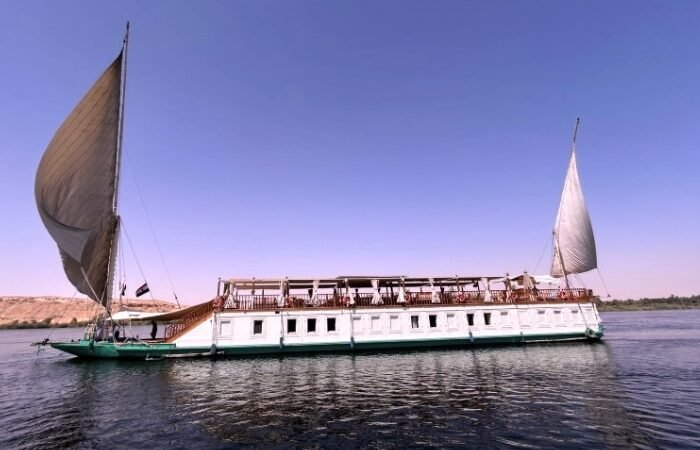 Dahabeya Queen Farida sailing on the Nile River with scenic views.