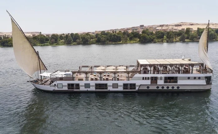 Luxury dahabiya sailing on the Nile River with scenic views.