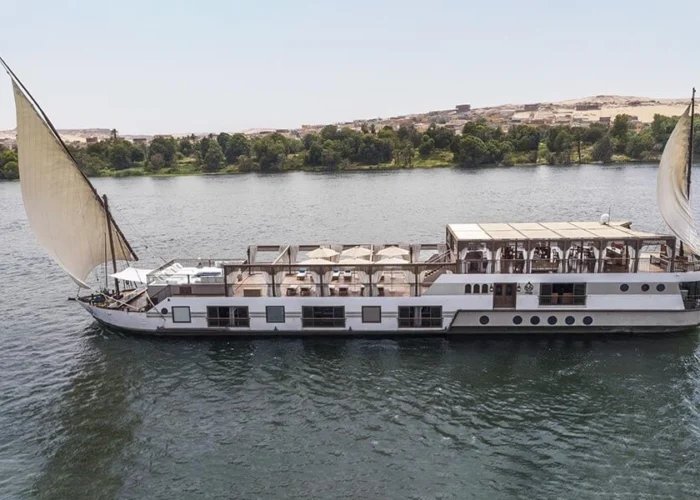 Luxury dahabiya sailing on the Nile River with scenic views.