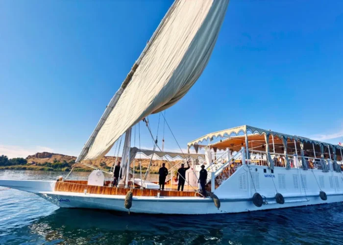 A white traditional Dahabiya sailing boat on the blue waters of the Nile River under a clear sky, illustrating why a private or small-group experience makes people ask, is Nile cruise worth it?